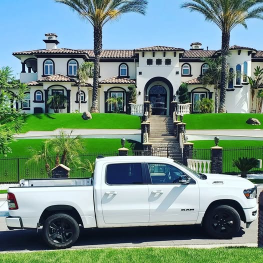 Picture of White truck in front of very large Mediterranean house.